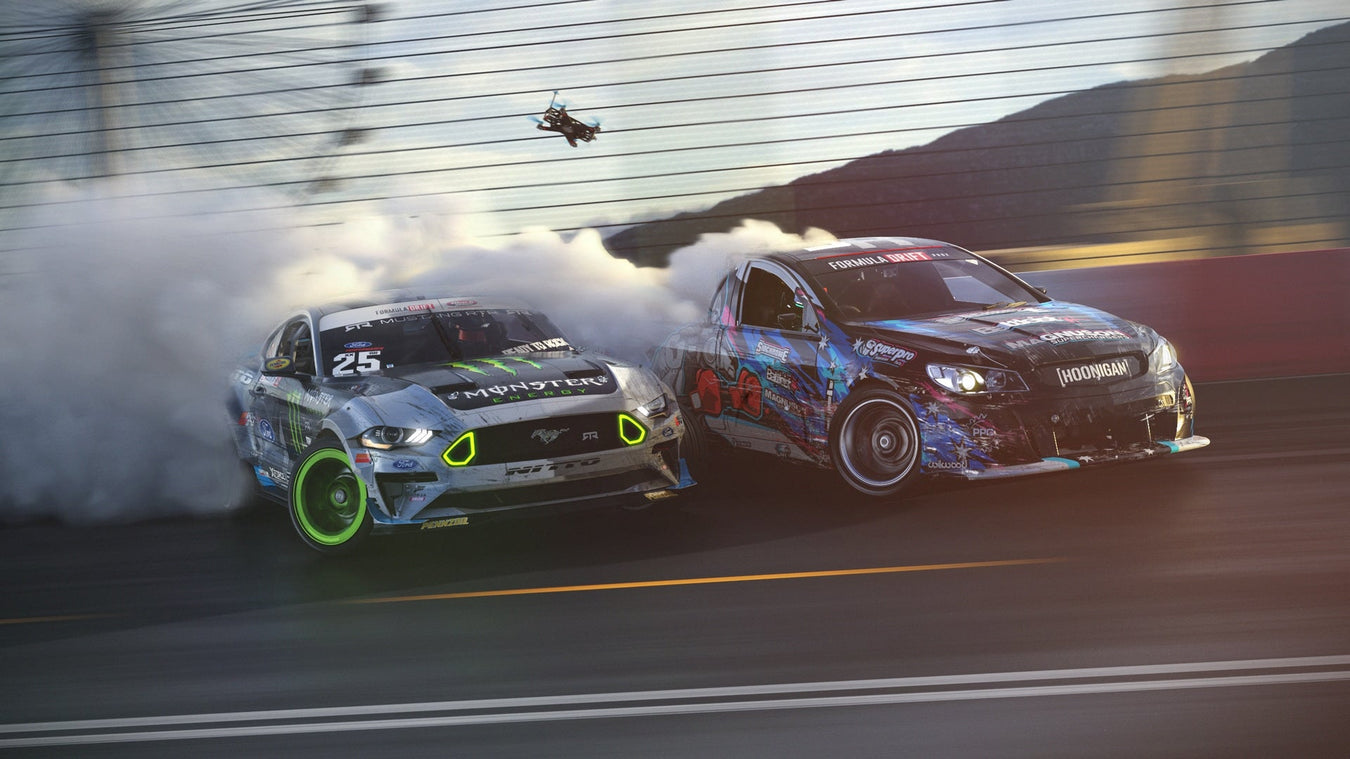 Monster Energy Ford Mustang drift car tandem drifting alongside a Hoonigan drift car with heavy tire smoke