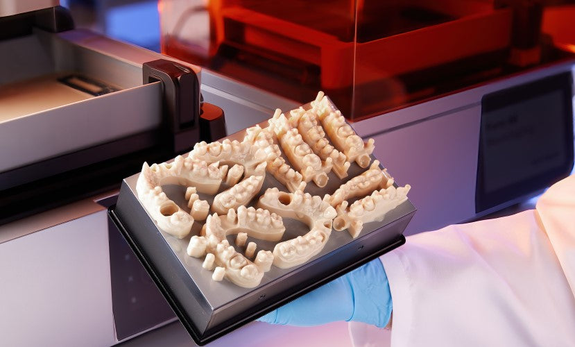 Image of a dental professional holding a Form 4 build platform with 3D printed Restorative models produced with Formlabs Precision Model resin