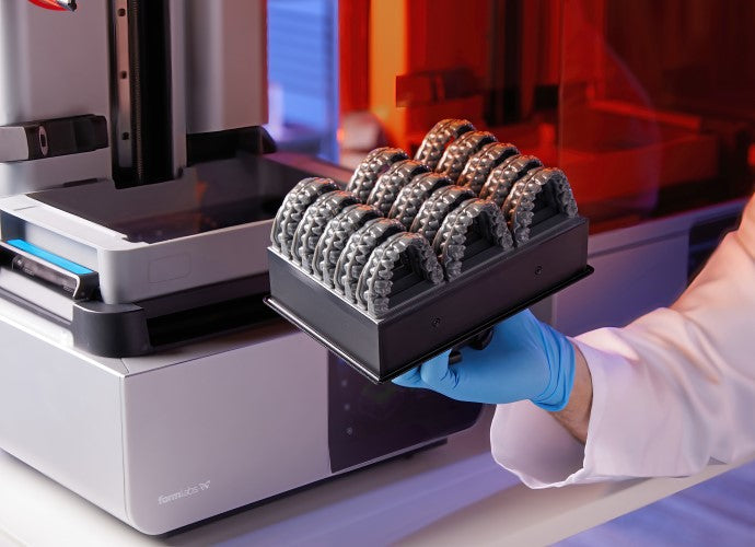 Formlabs Grey V5 Resin for Formlabs Form 4 SLA 3D printer | Image of a dental professional holding a Form 4 build platform with 3D printed dental models