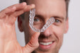 Image shows a man holding a clear bite splint 3D-printed with Formlabs Dental LT Comfort resin